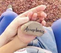 Picture of an adult and child holding a rock saying acceptance